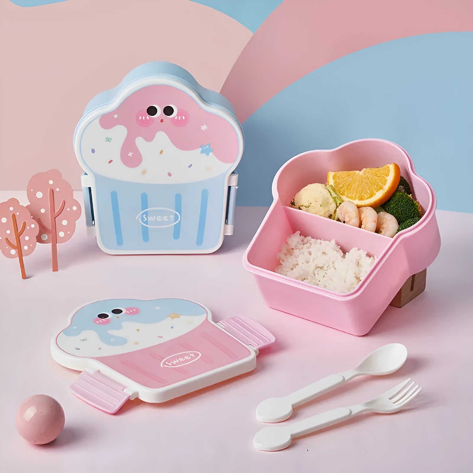 Pink and blue creative ice cream shaped plastic lunch box with compartments, shown with matching spoon and fork.