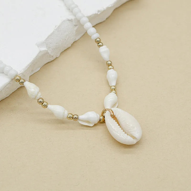 White conch shell pendant and bead necklace on a regular chain.