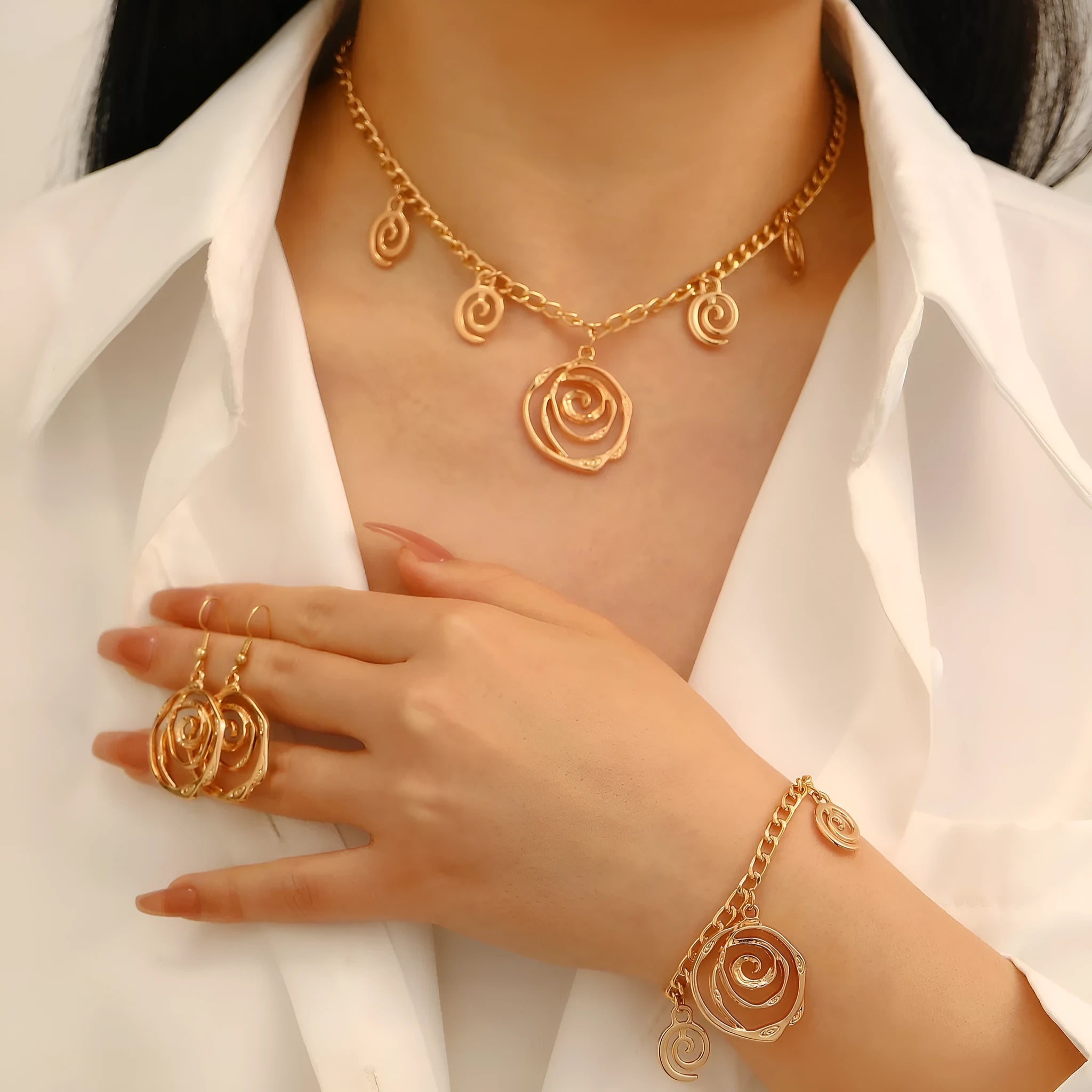 Spiral donut design necklace, bracelet, and ear hook set in gold or silver plating on a dark background.