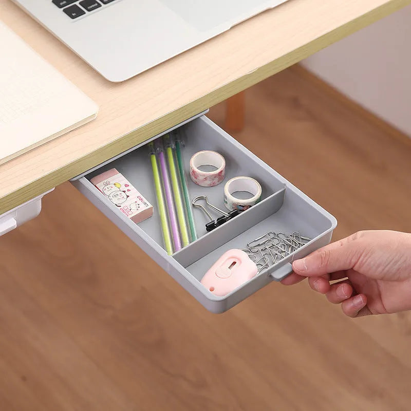 Adhesive under table storage drawer in plastic with covered grid design, shown in grey colour