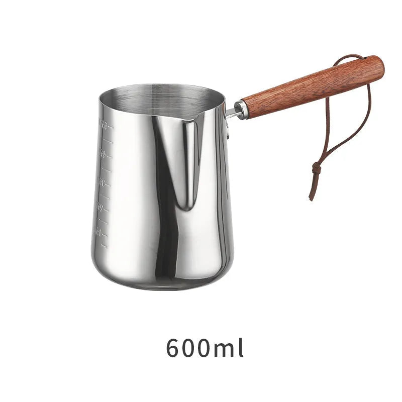 Stainless steel coffee mug with measurement scale and a light wood handle on a wooden table.