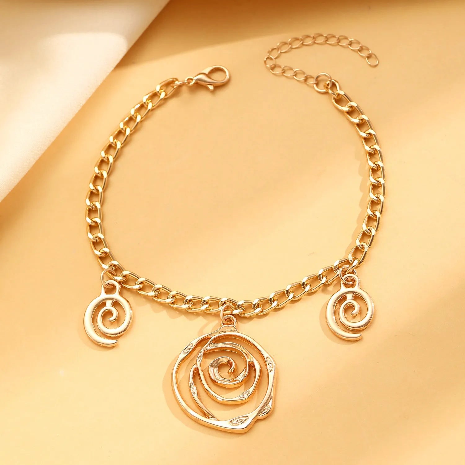 Spiral donut design necklace, bracelet, and ear hook set in gold or silver plating on a dark background.