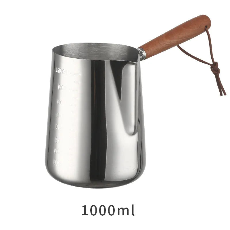 Stainless steel coffee mug with measurement scale and a light wood handle on a wooden table.