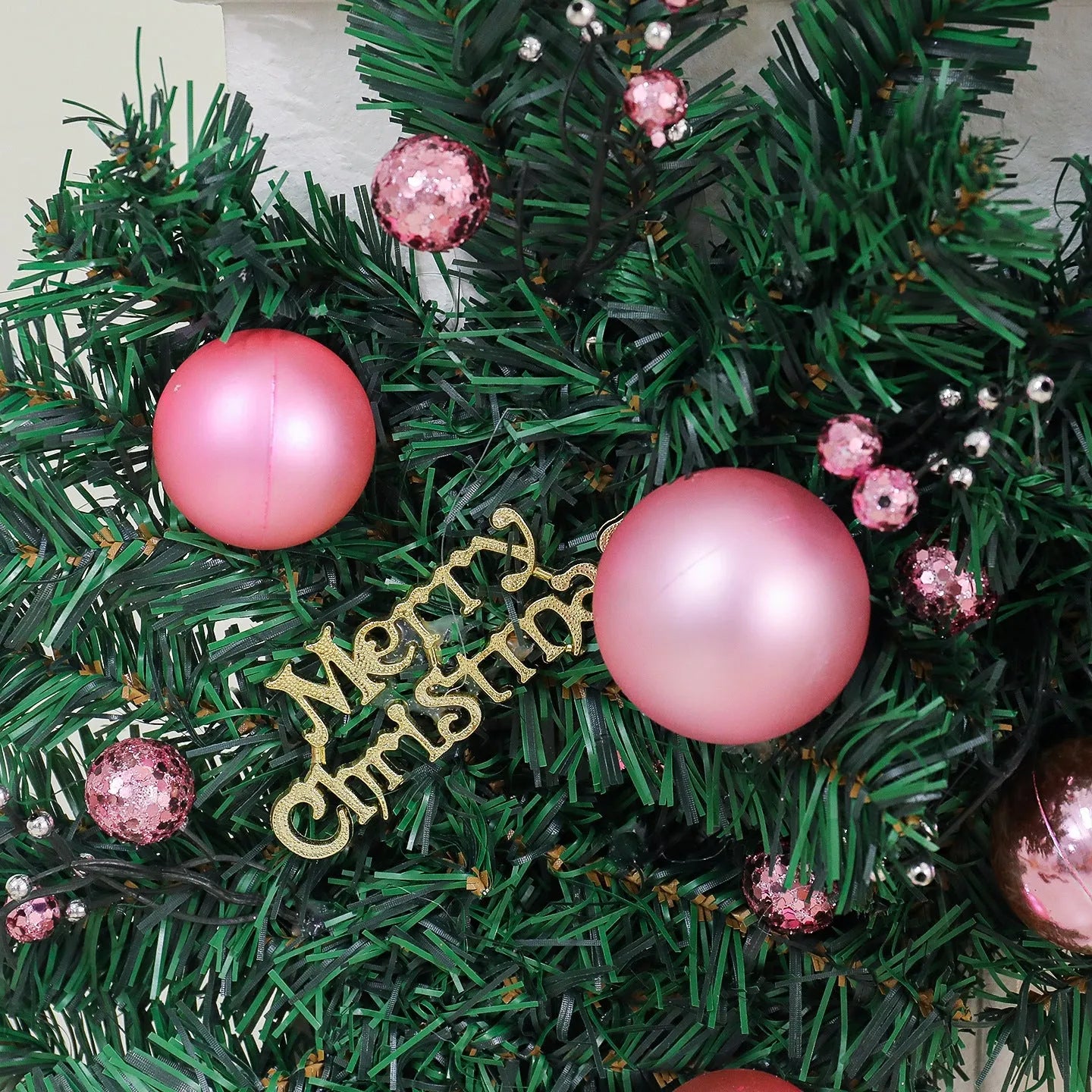Pink artificial rattan Christmas garland with small fruit details and warm white LED lights, coiled to show its 2.7m length.