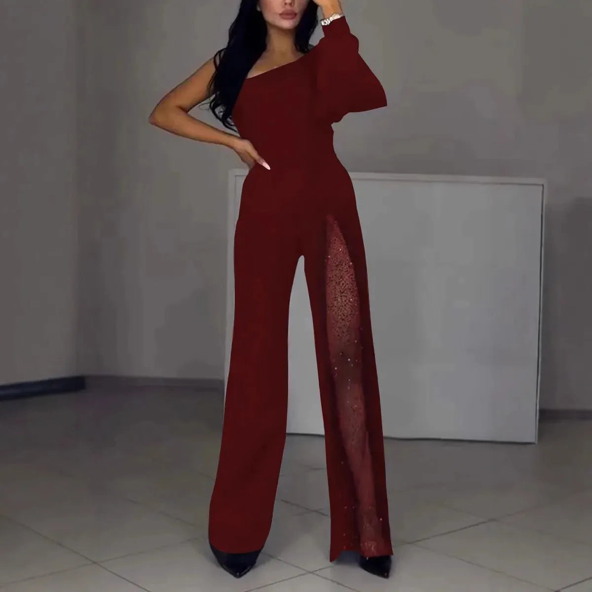 Women's black jumpsuit with an oblique asymmetric shoulder cut and a high slit on the leg.