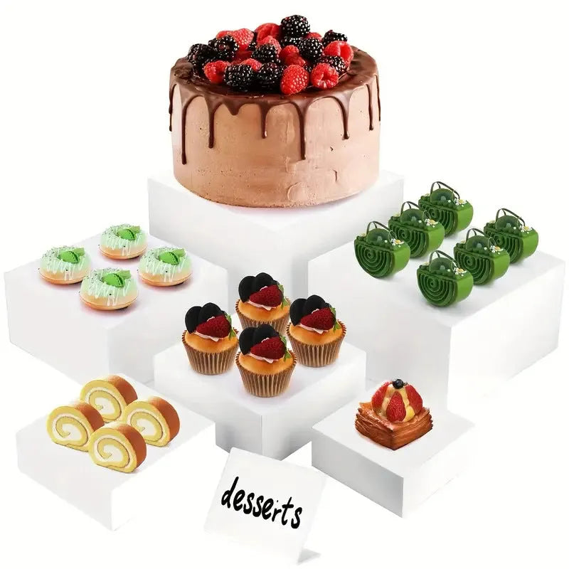 White plastic dessert table display stand with six cube-shaped racks for cakes and pastries.