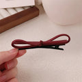 Wine red leather bow hair barrette showing bow design and clip mechanism