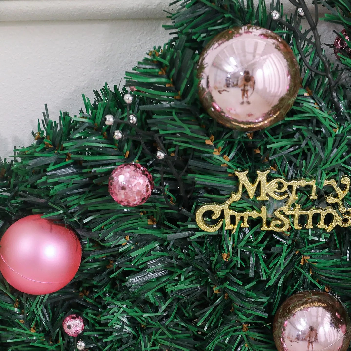Pink artificial rattan Christmas garland with small fruit details and warm white LED lights, coiled to show its 2.7m length.