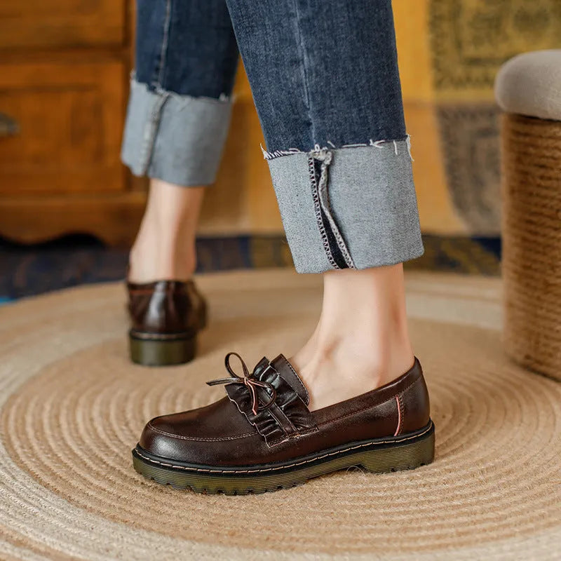 Women's black leather shoes with round toe, chunky flat heel, and low-top design on a white background.