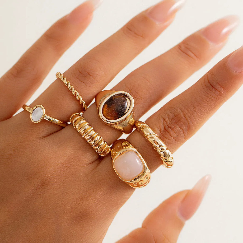 Six geometric alloy rings with irregular designs in light gold colour arranged together