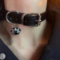 Black adjustable dog collar with small bell charm shown in leather, bone, and cat's paw designs.