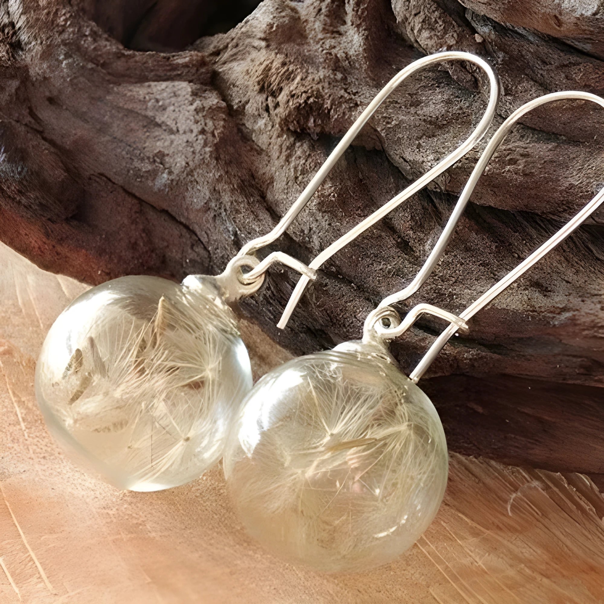 Transparent glass ball earrings on a French hook, showing dandelion seed design in silver and bronze finishes.