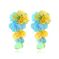 Close-up of handmade colourful bead flower and leaf statement earrings on a white background.