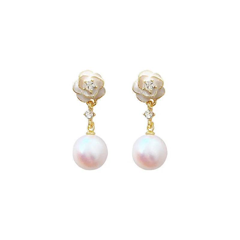 Close-up of a pair of pearl-finished camellia flower stud earrings made from alloy metal.