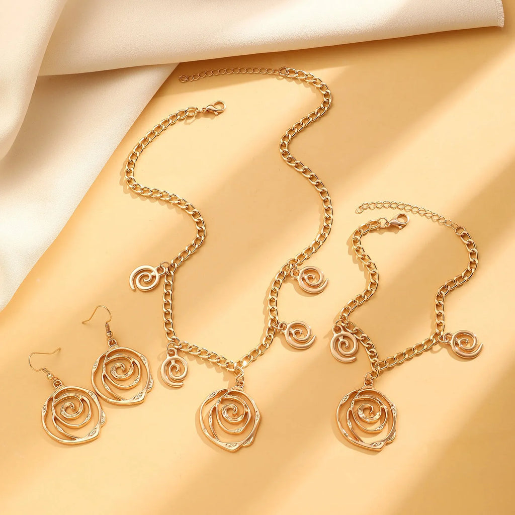 Spiral donut design necklace, bracelet, and ear hook set in gold or silver plating on a dark background.