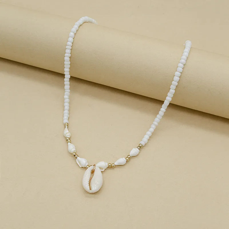 White conch shell pendant and bead necklace on a regular chain.