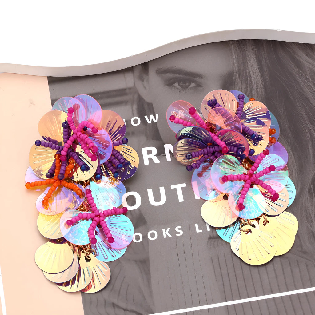 Close-up of handmade colourful bead flower and leaf statement earrings on a white background.