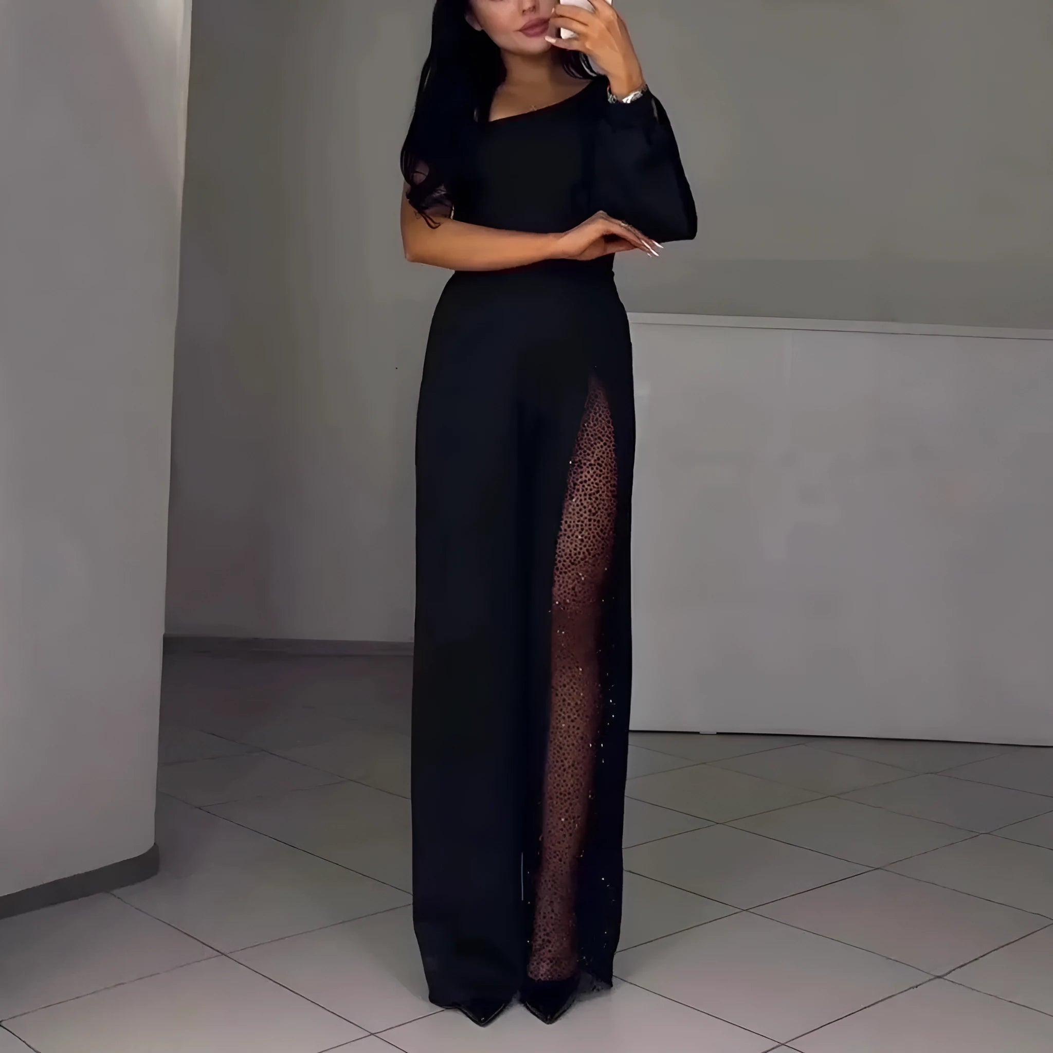 Women's black jumpsuit with an oblique asymmetric shoulder cut and a high slit on the leg.