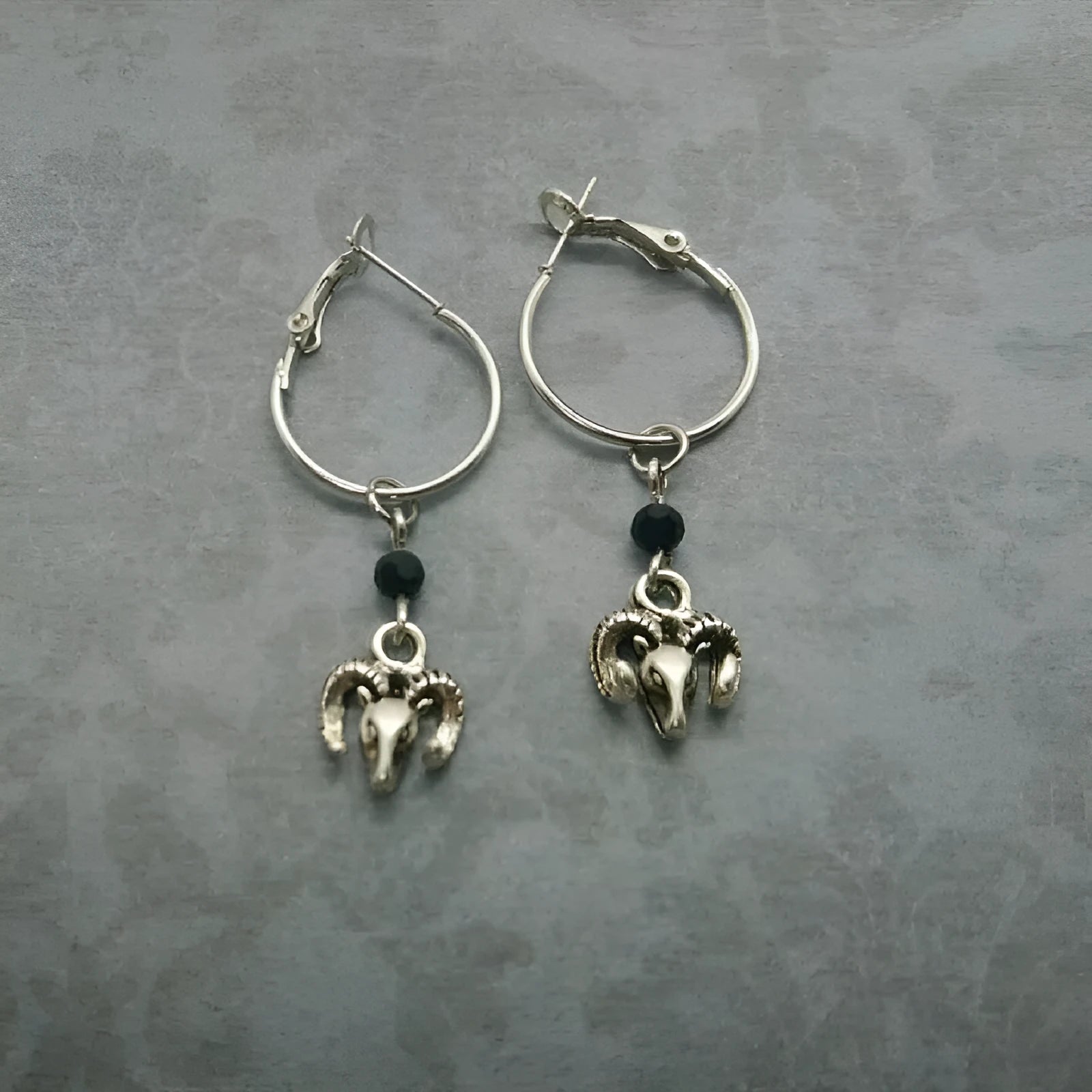 Silver coloured round alloy earrings featuring an engraved Tibetan antelope design.