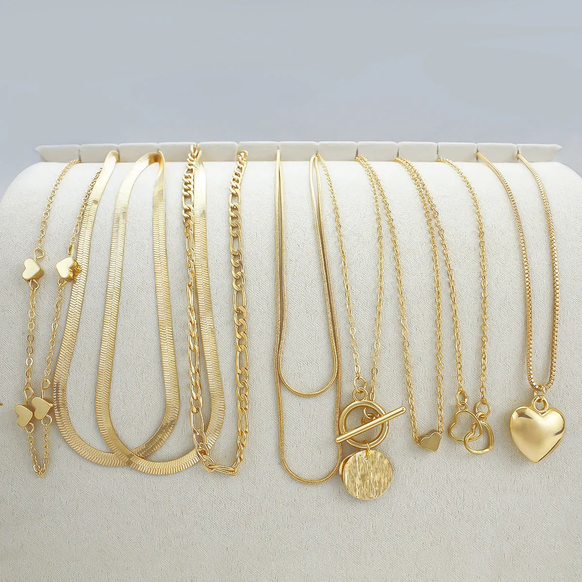 Gold-coloured women's necklace set showing ten pieces with simple alloy pendants on snake bone chains
