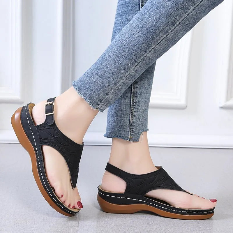 Women's black casual wedge heel flip flop sandals showing adjustable back buckle strap and solid colour design.