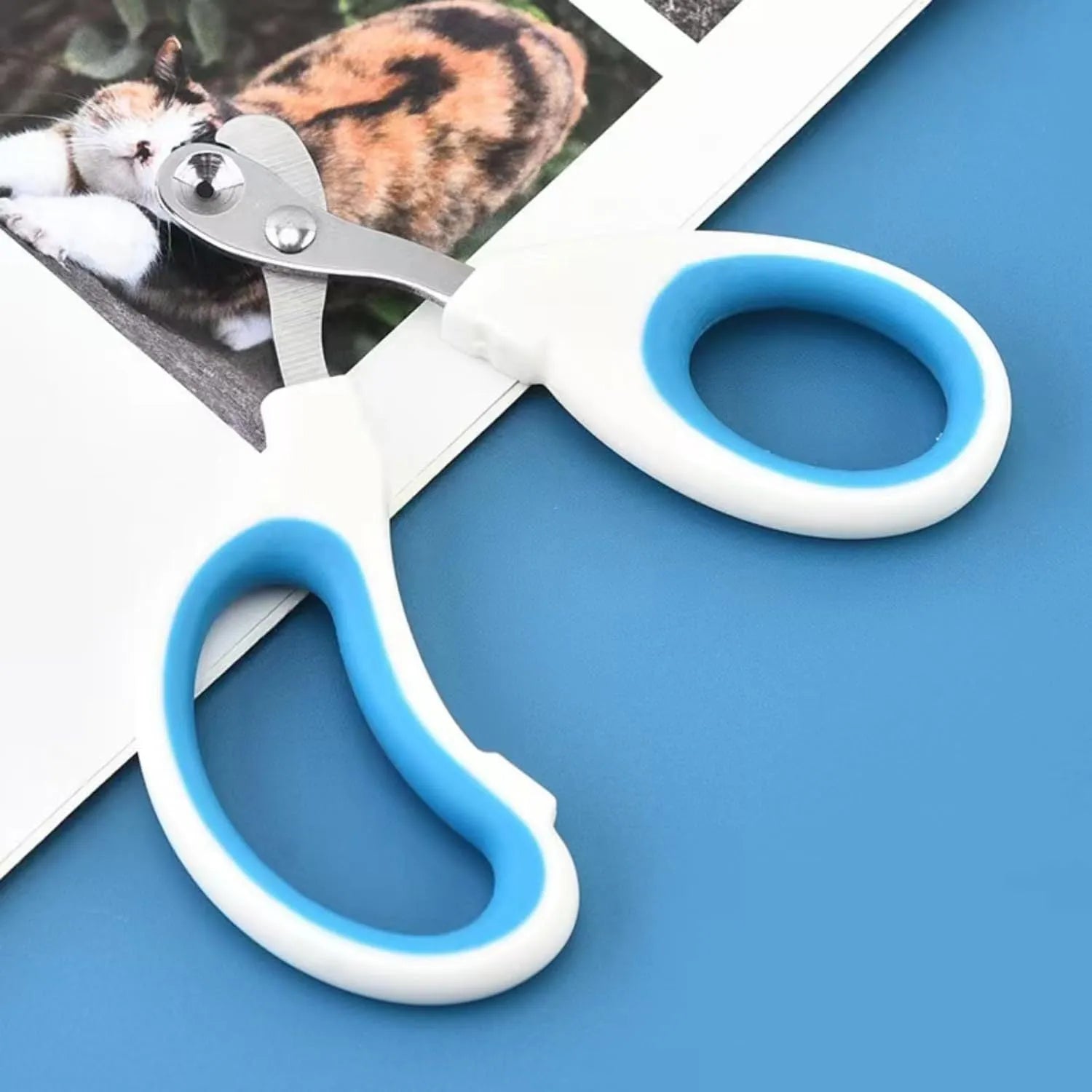 Blue cat nail clippers with a circular cutting hole and cushioned non-slip handle on a white background.