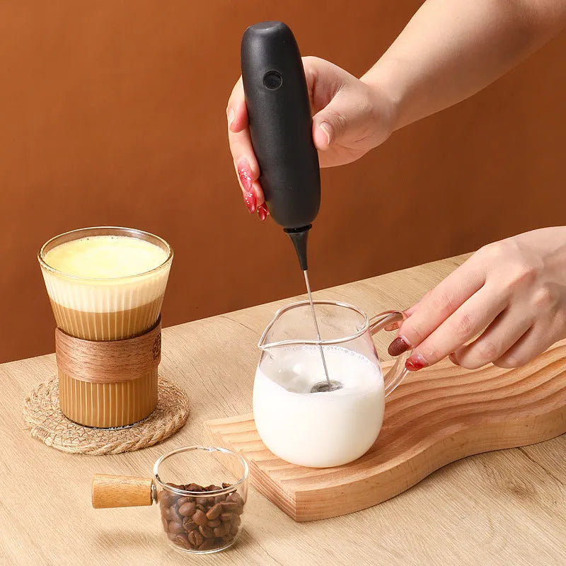 Black and white electric hand-held milk frother for coffee drinks