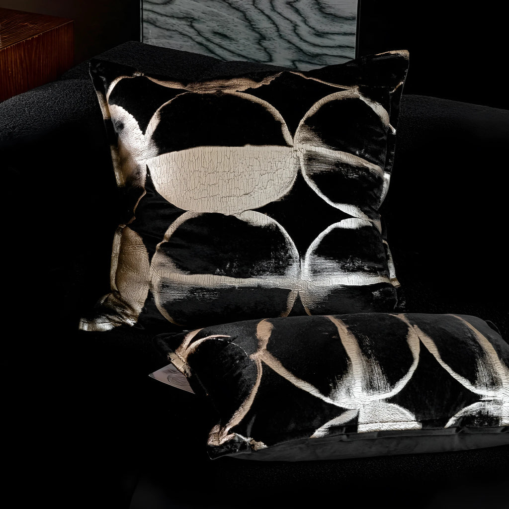 Black and gold abstract pattern flannel decorative cushion on a grey sofa.