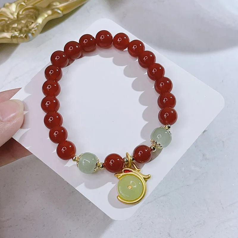 A red agate bracelet for women with Chinese style dragon and lucky bag motifs.
