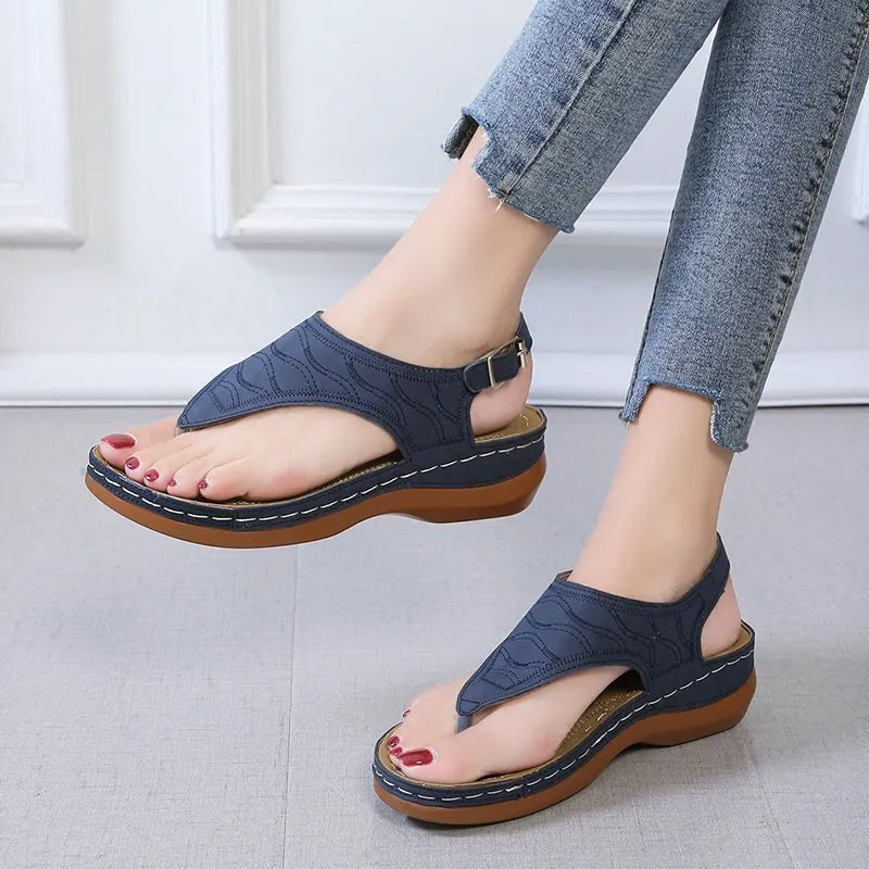 Women's black casual wedge heel flip flop sandals showing adjustable back buckle strap and solid colour design.
