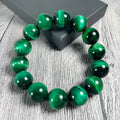 Polished green tiger eye stone bracelet with geometric beads in various sizes on wrist