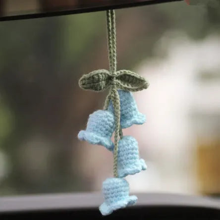 Green and white knitted wool car plant decoration with white hanging rope.