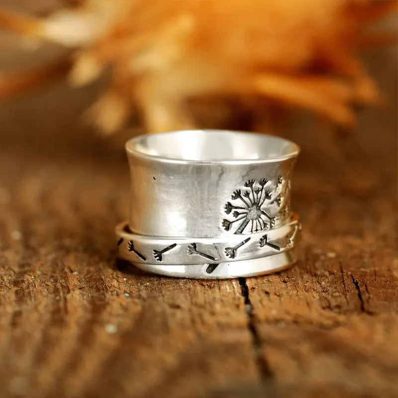 Silver rotatable flower ring on a finger showing the floral design.