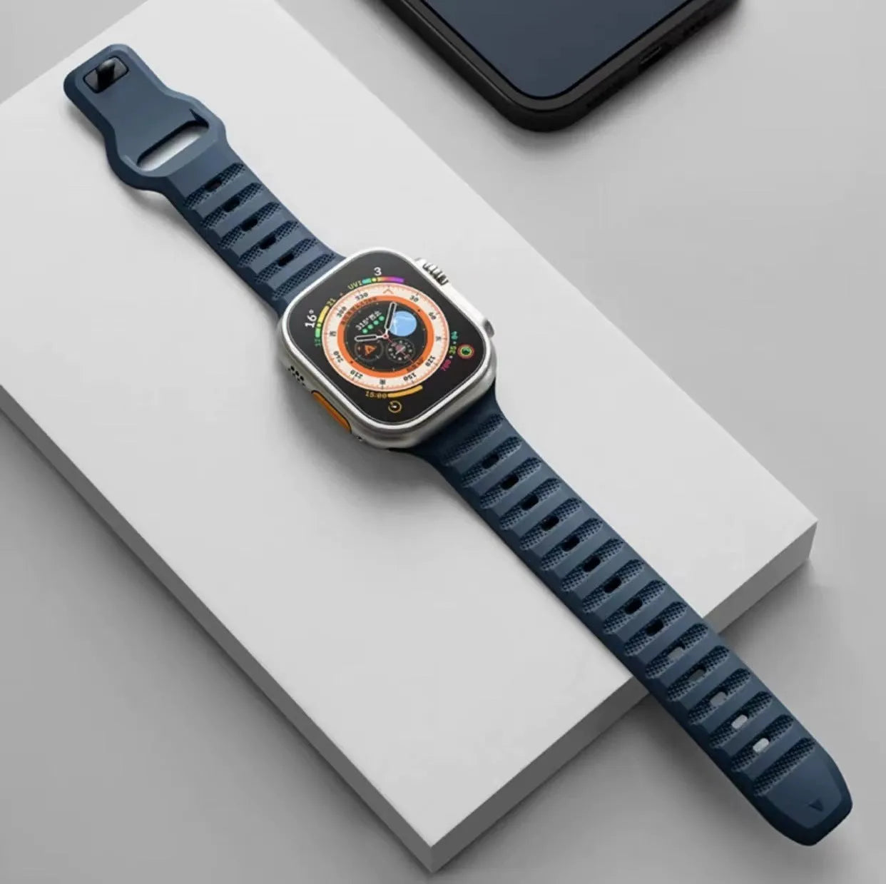 Fluoro rubber Apple Watch band with T-buckle in multiple colours on a grey background
