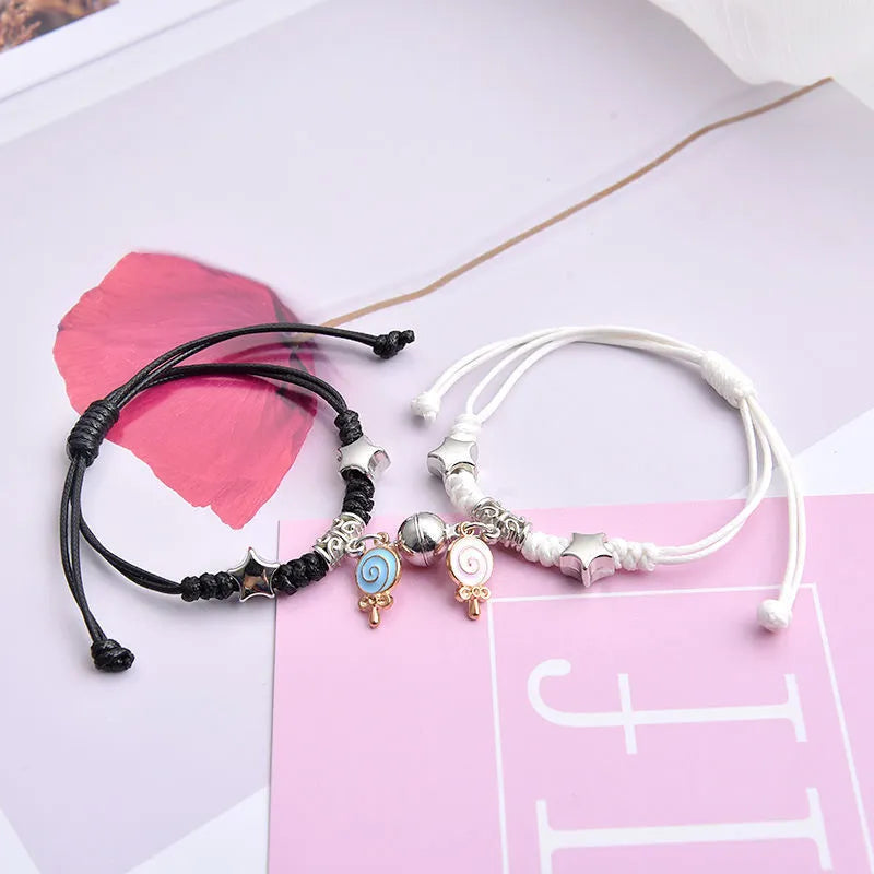 Pair of magnet couple bracelets with suction clasp on wrist, showing alloy designs like crown and love lock.