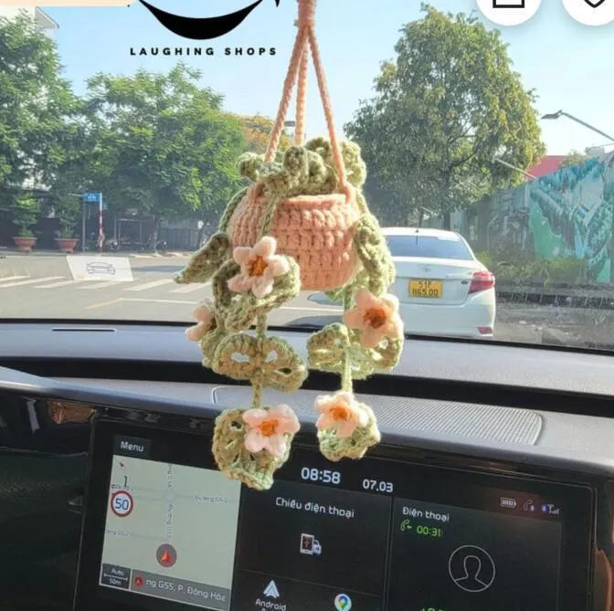 Green and white knitted wool car plant decoration with white hanging rope.