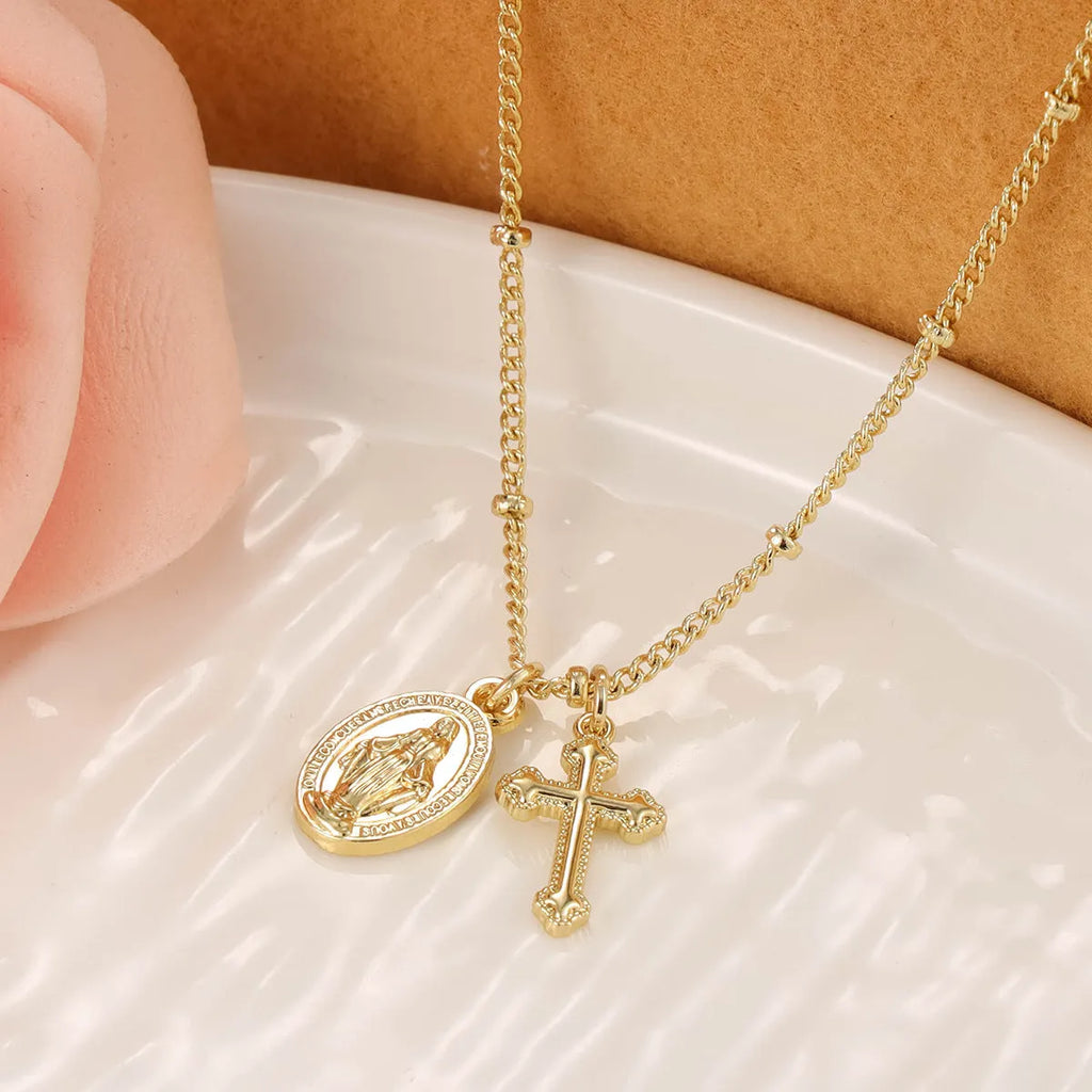 Gold geometric cross and Virgin Mary pendant necklace on display