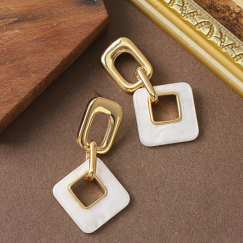 A pair of hollow geometric square copper earrings with a chamfered pattern design.