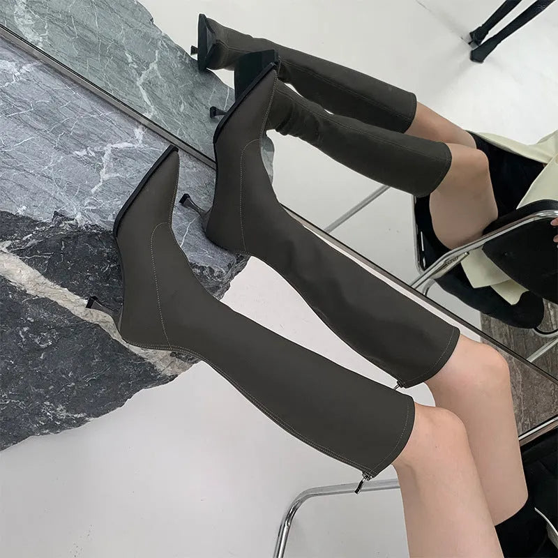 Black women's pointed toe stiletto heel boots with a back zipper, shown below the knee.