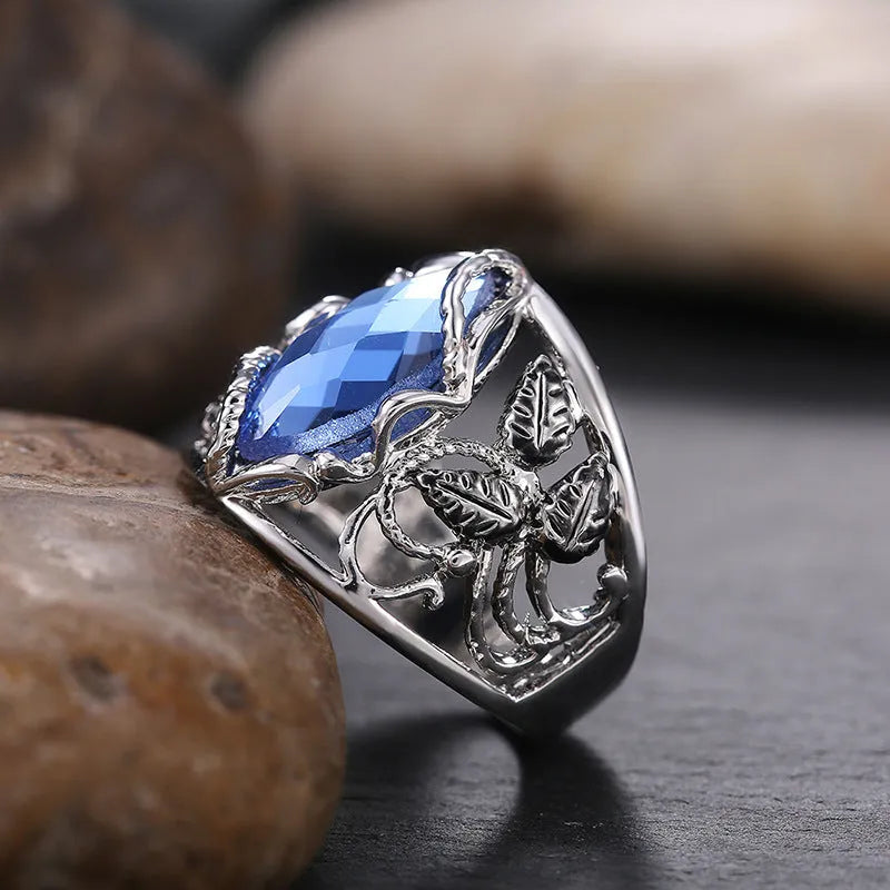 Close-up of a women's horse eye shaped blue crystal ring on a finger.