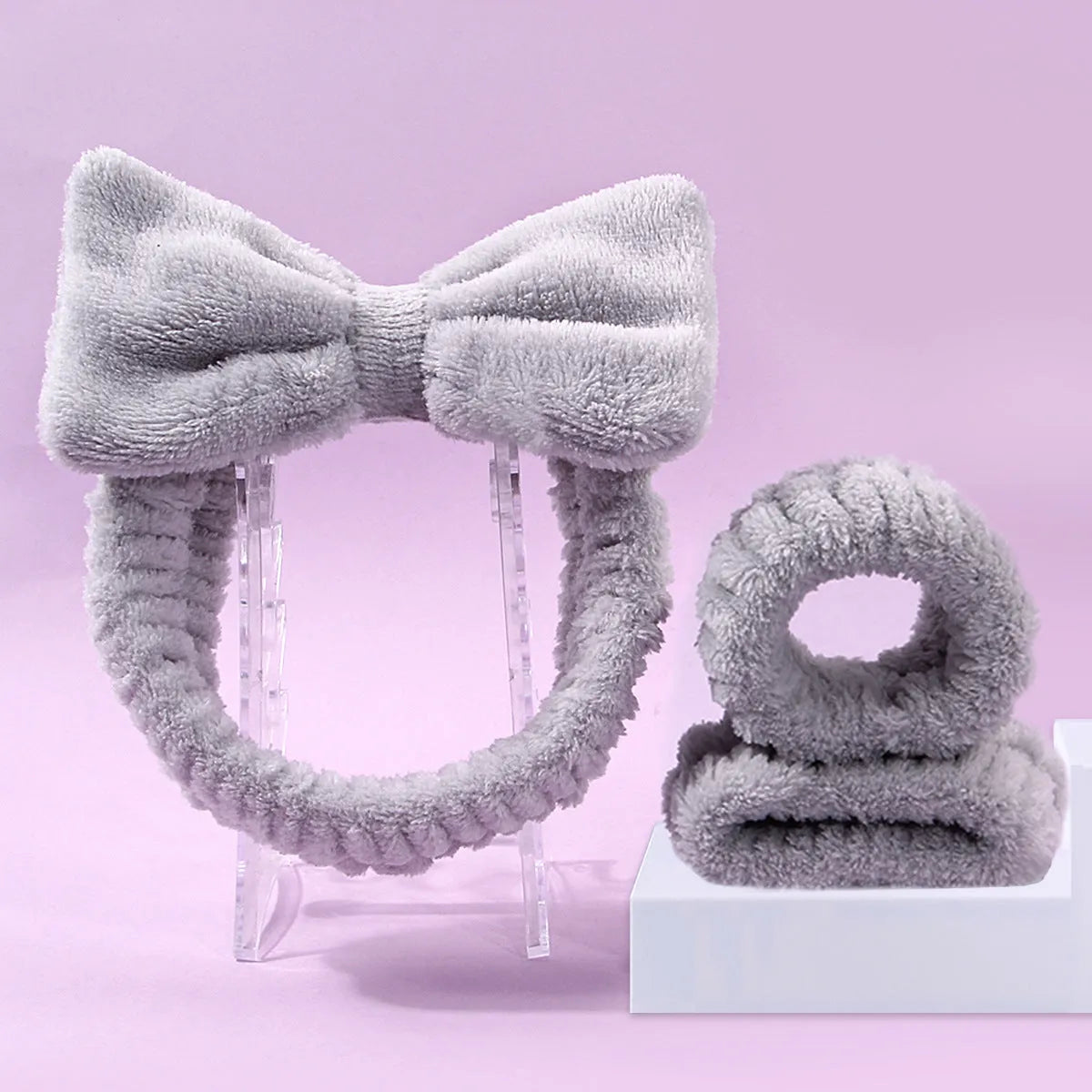 Keep dry facial brush set with plastic handle, coral fleece hair band, and stack of purple and pink face wash sponge suits.