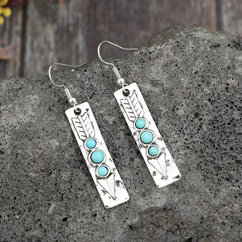 Silver geometric drop earrings with turquoise inlay details on white background