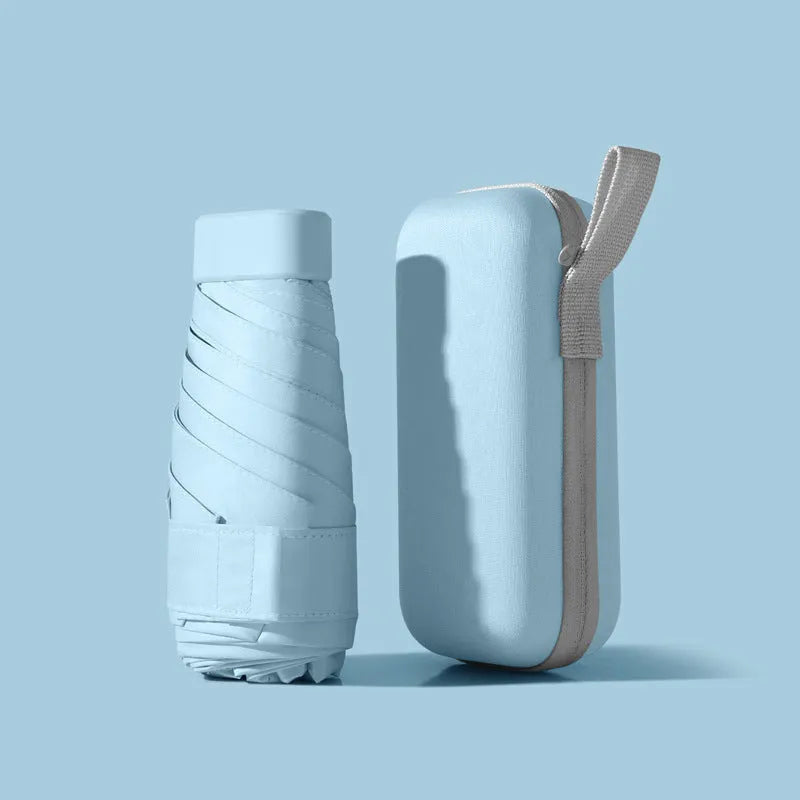 A folded six-fold flat umbrella in a capsule box, showing the steel ribs and rubber handle.