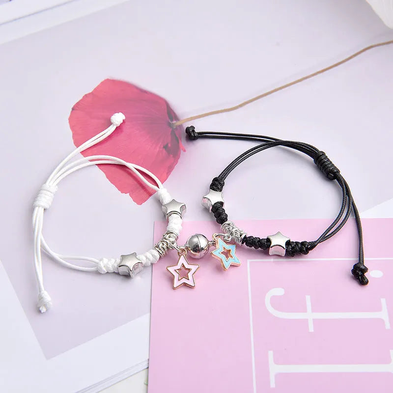Pair of magnet couple bracelets with suction clasp on wrist, showing alloy designs like crown and love lock.