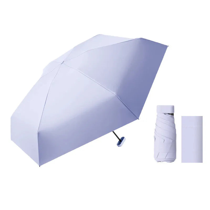 A folded six-fold flat umbrella in a capsule box, showing the steel ribs and rubber handle.