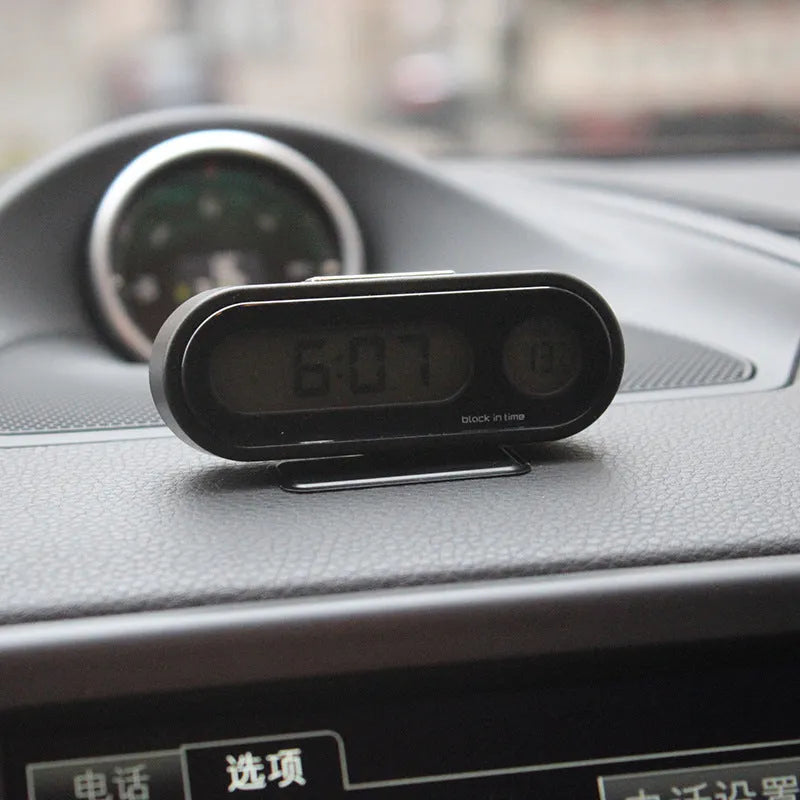 Black electronic car clock and thermometer unit with LED display on adjustable bracket.