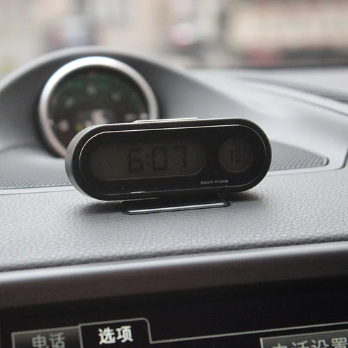 Black electronic car clock and thermometer unit with LED display on adjustable bracket.