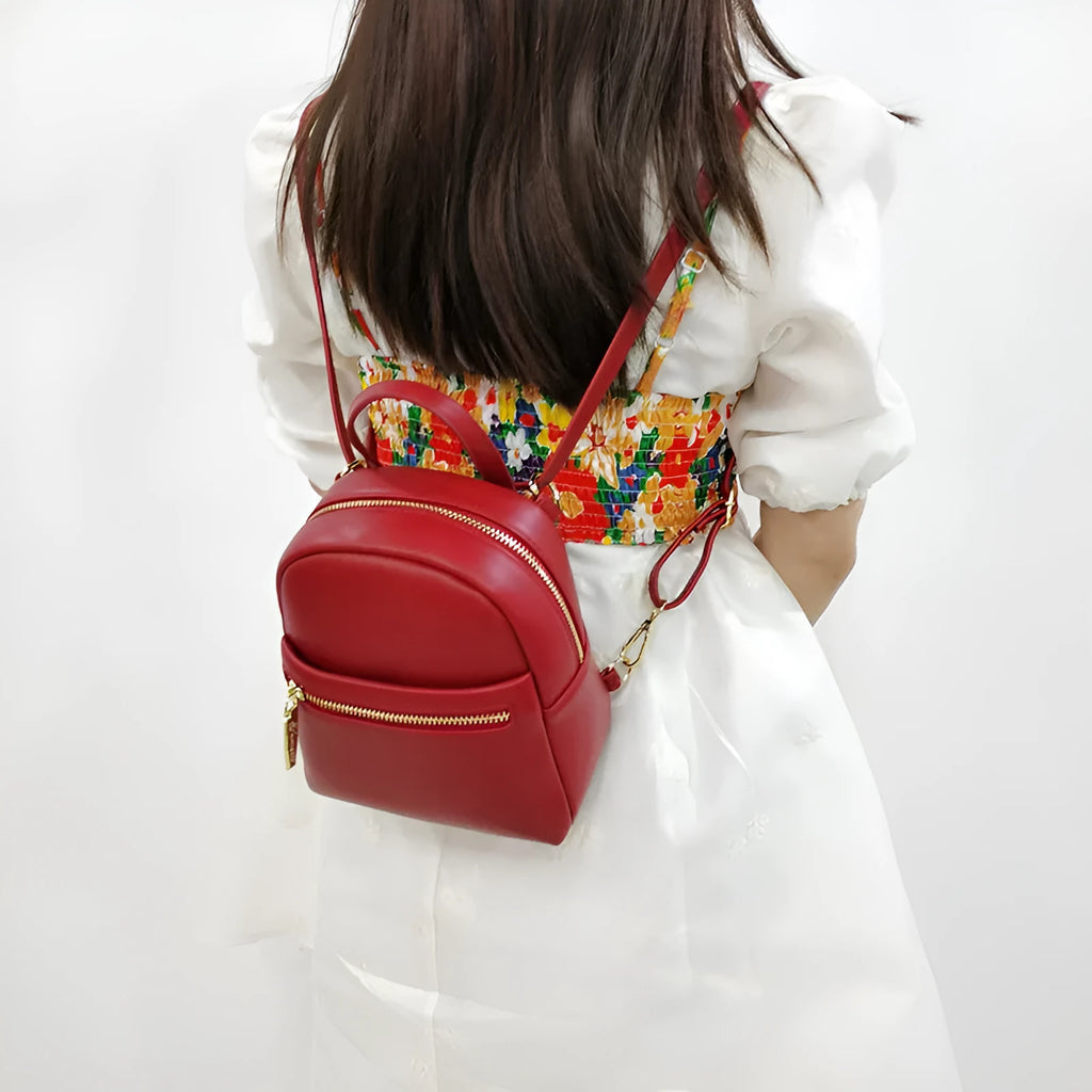 Soft black PU mini backpack with front pockets, shown open to reveal internal mobile phone sleeve and zipper compartment.
