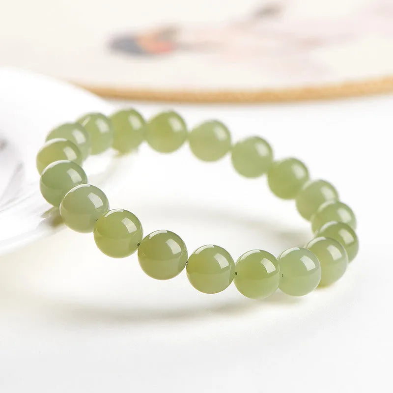 A polished Hetian jade bead bracelet in a light ice-clear colour, showing smooth round beads on a string.