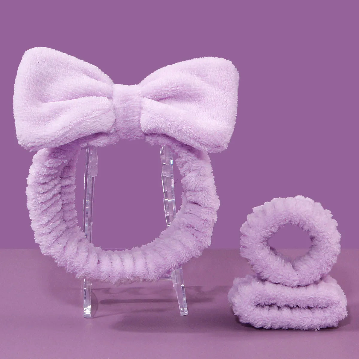 Keep dry facial brush set with plastic handle, coral fleece hair band, and stack of purple and pink face wash sponge suits.